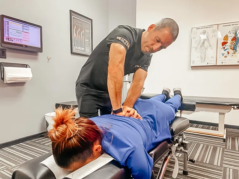 Chiropractor performing spinal adjustment on patient lying face-down