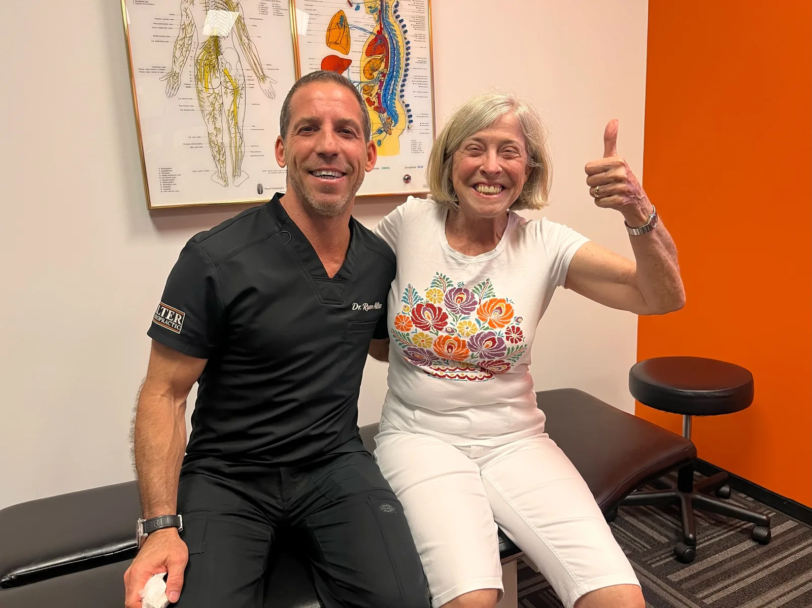 Chiropractor and smiling patient give thumbs up together